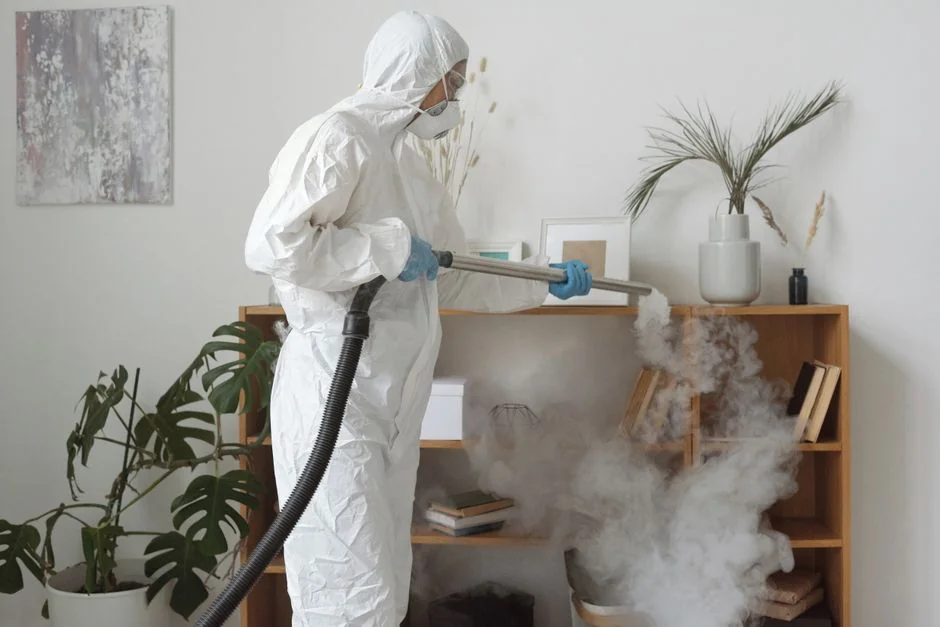 Des mains gantées nettoient les poignées d’un meuble avec un vaporisateur et un chiffon pour l’hygiène.