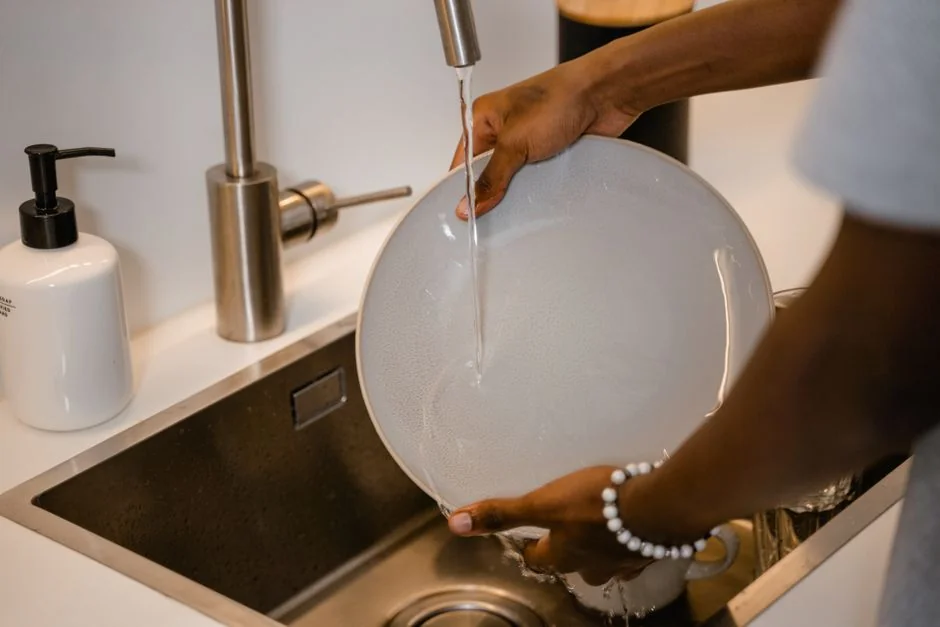 who-we-are Close-up of gloved hands disinfecting a remote control with a cloth and spray bottle.
